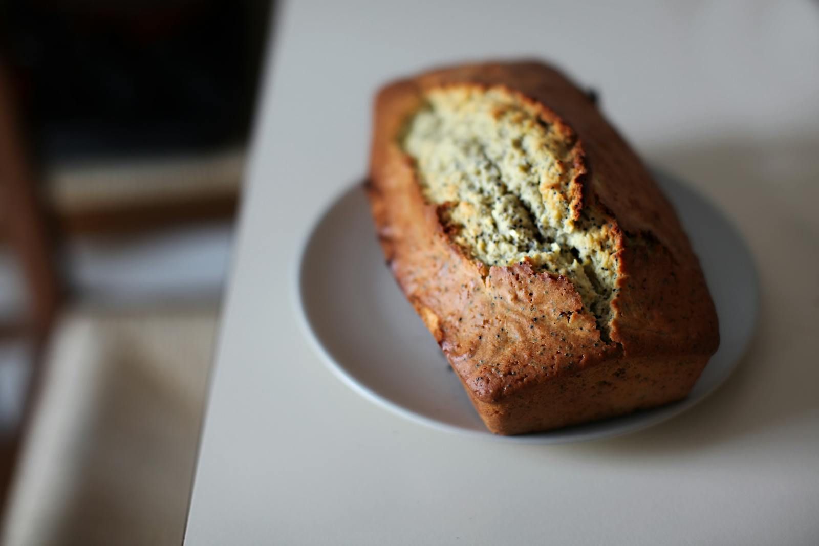 A loaf of dark-crusted banana bread on parchment, sliced to show a tender amber crumb.