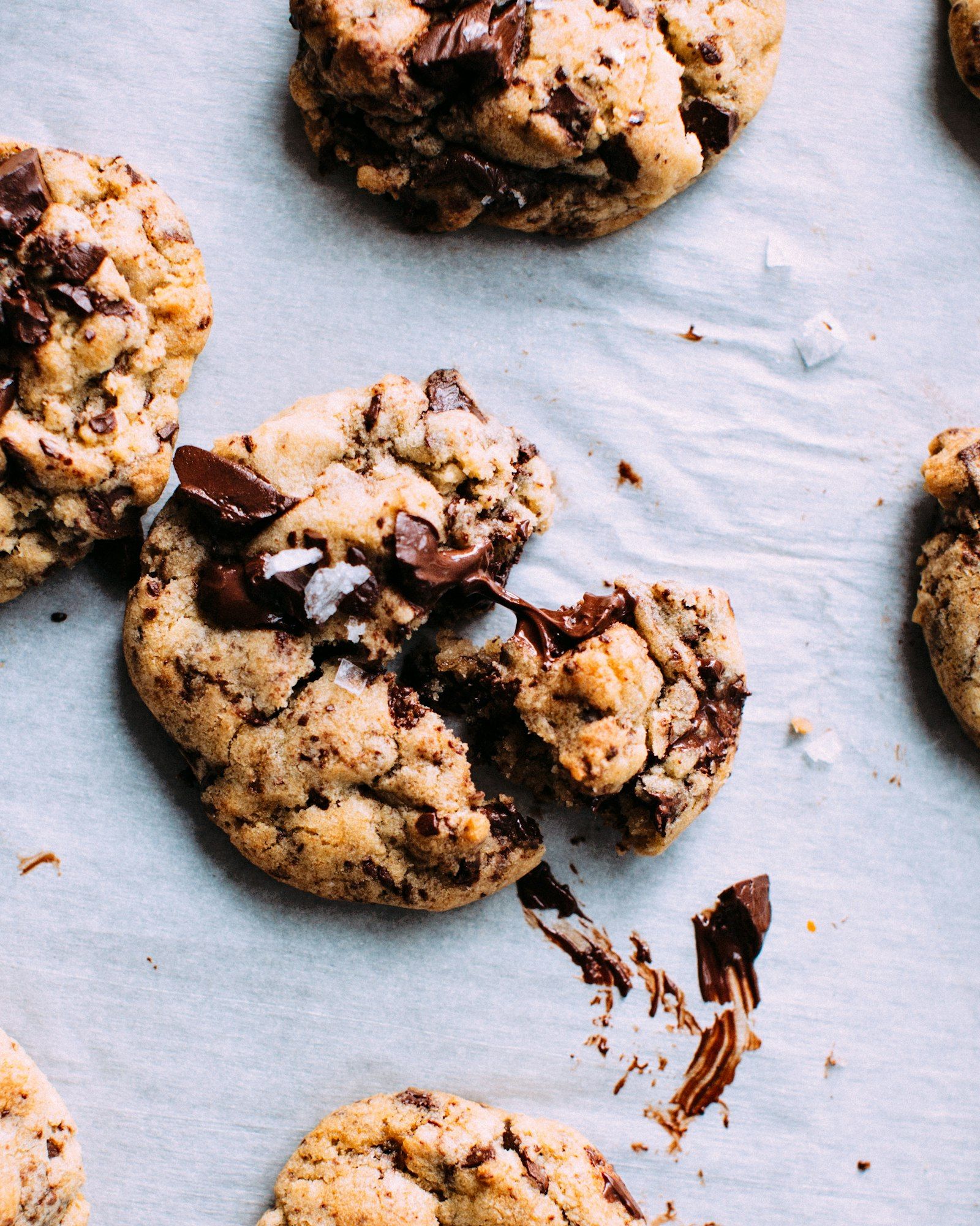 A stack of chocolate chip cookies with golden crisp edges, gooey chocolate centers, and flaky salt on top.